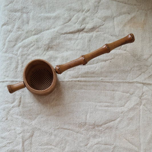 Brown, natural carved bamboo strainer with handle and mug rest. 